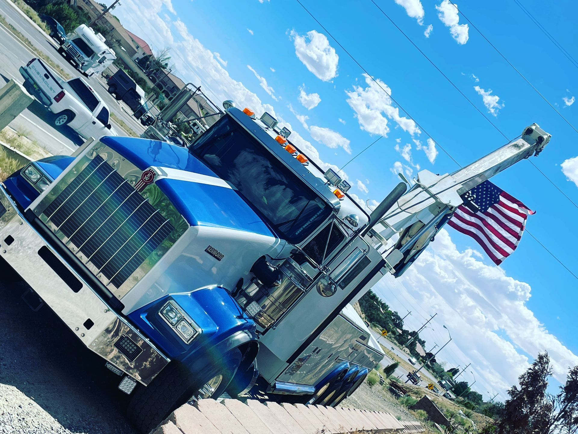 A blue and white tow truck is parked on the side of the road.