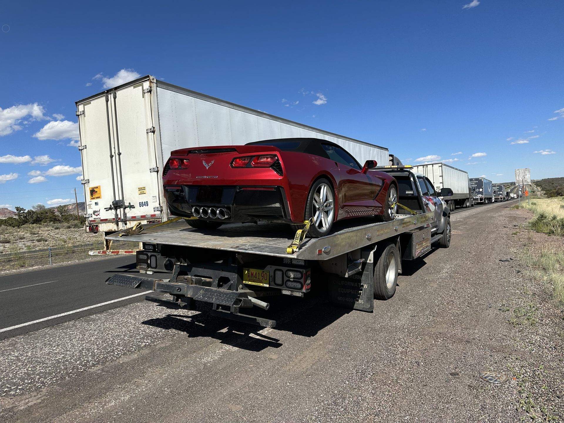 A red corvette is sitting on top of a tow truck.