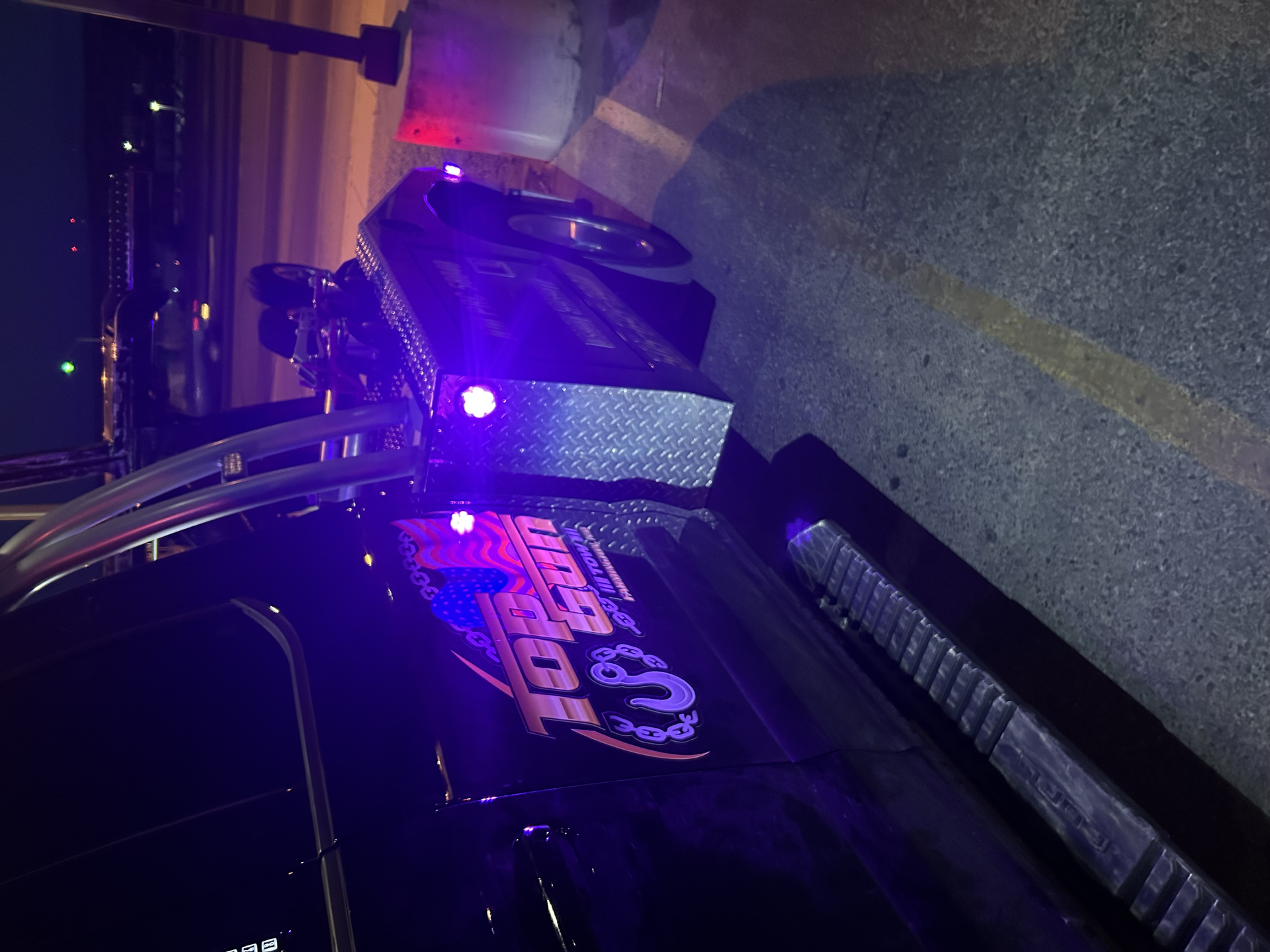 A tow truck is parked on the side of the road at night.