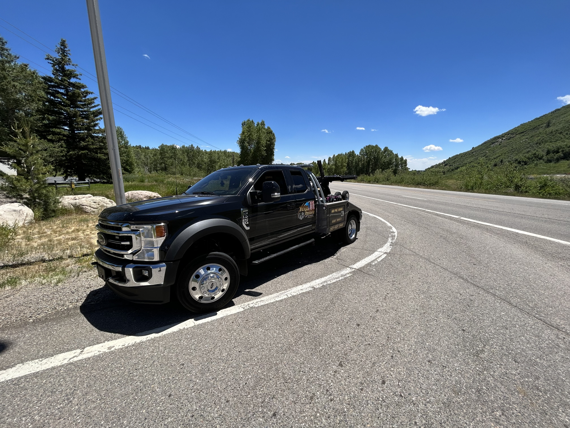 A black truck is parked on the side of a curvy road.