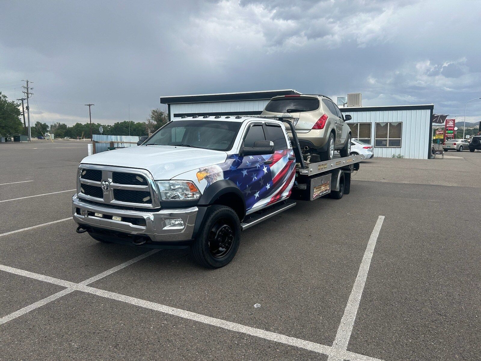 A tow truck is towing a car in a parking lot.
