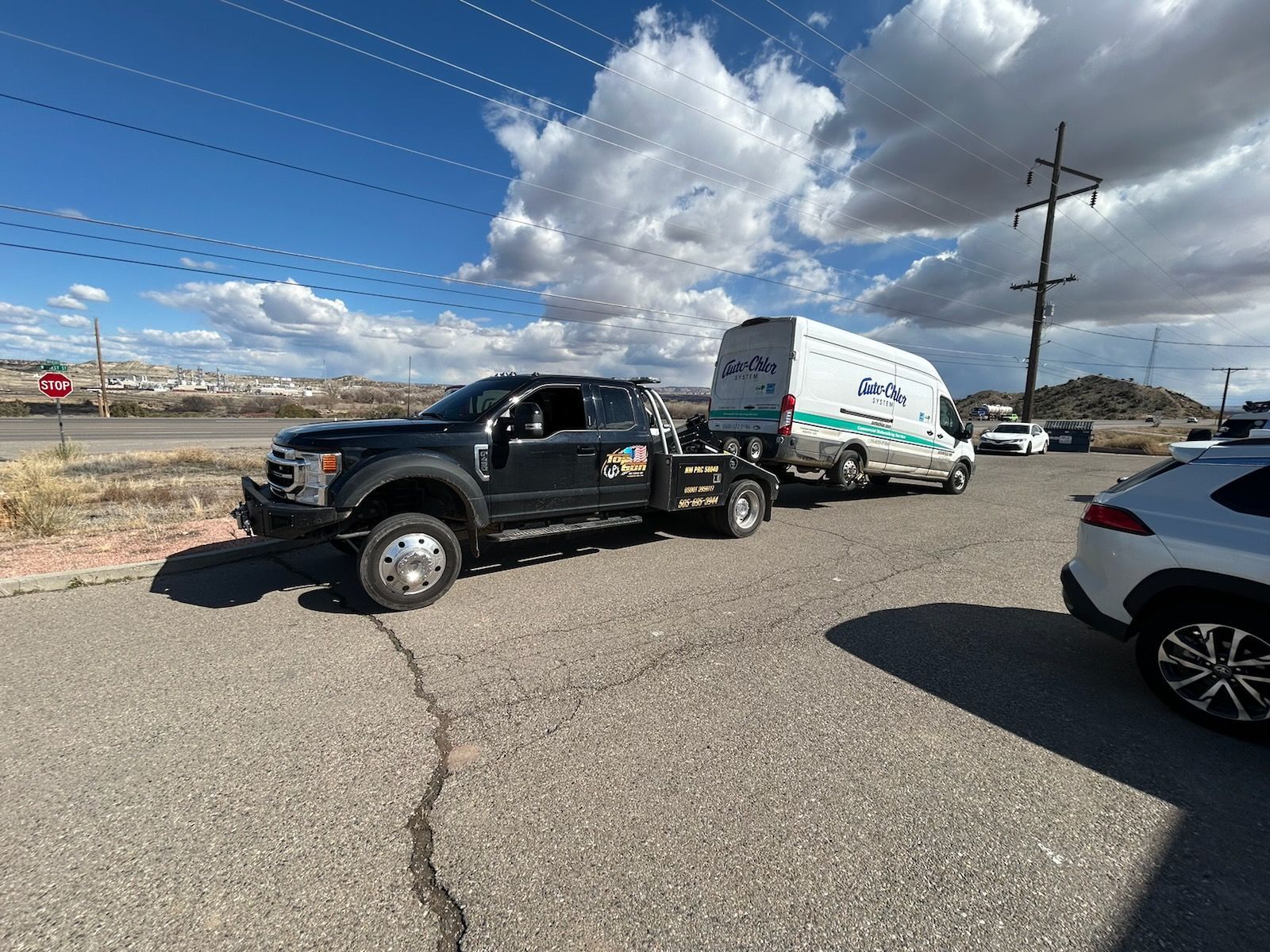A tow truck is towing a white van down a road.