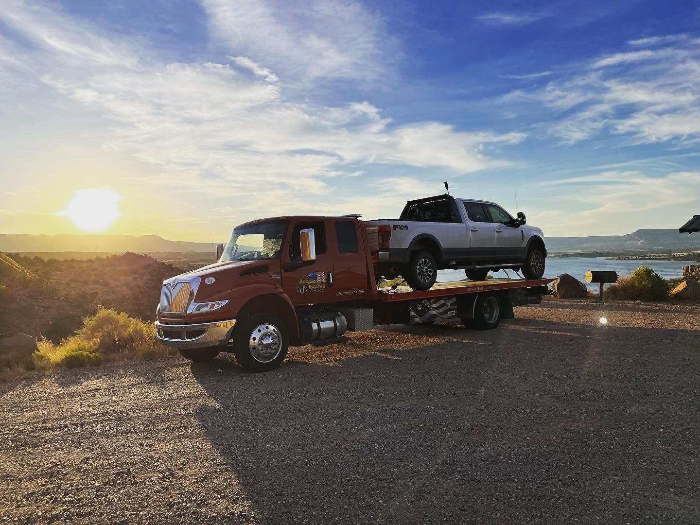 A tow truck is carrying a truck on the back of it.