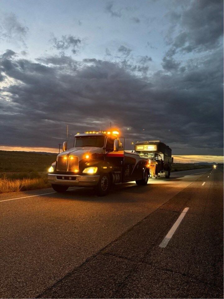 A tow truck is driving down a highway at night