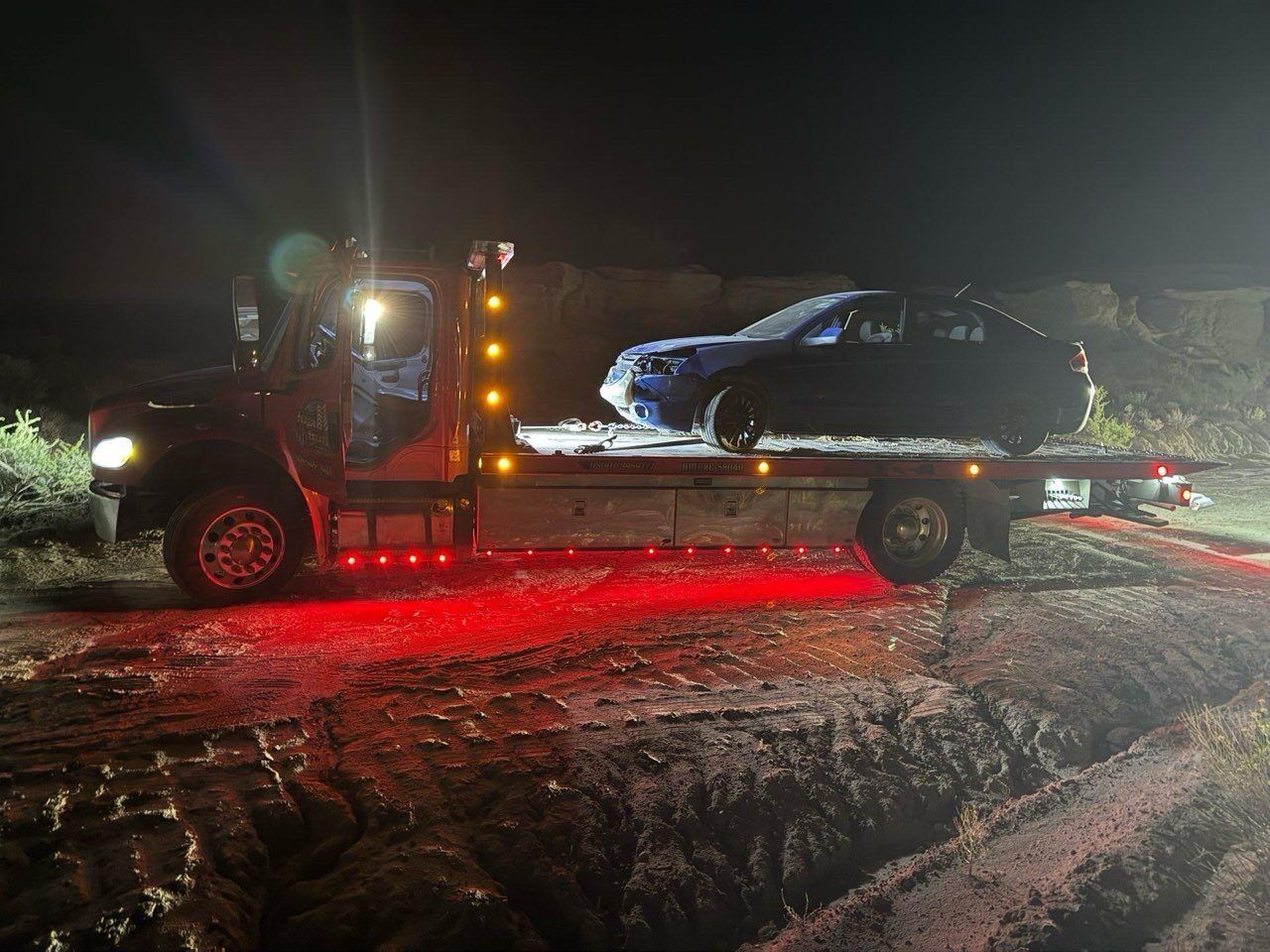 A tow truck is carrying a car on the back of it.