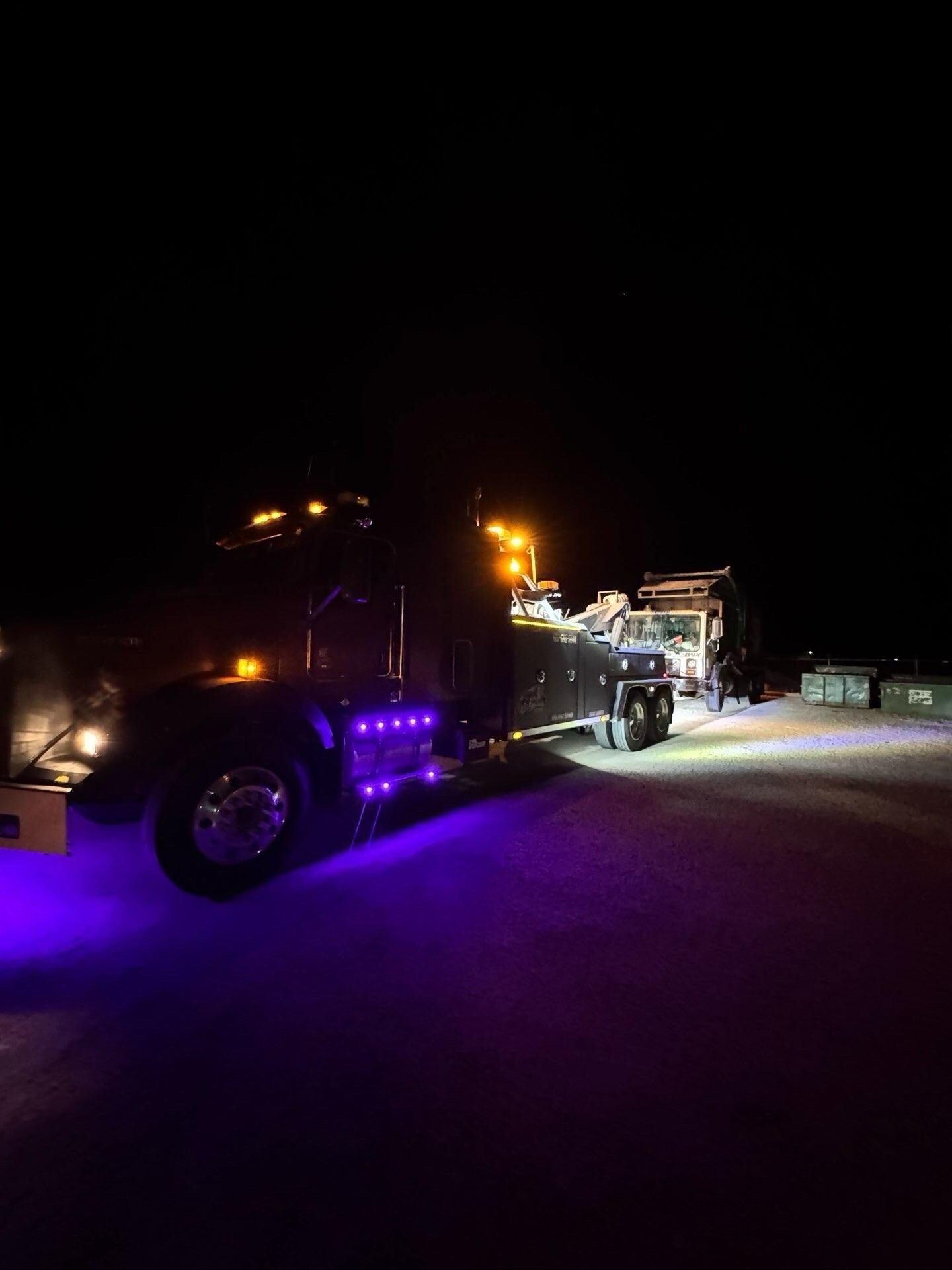 A truck is parked in the snow at night with purple lights on it.
