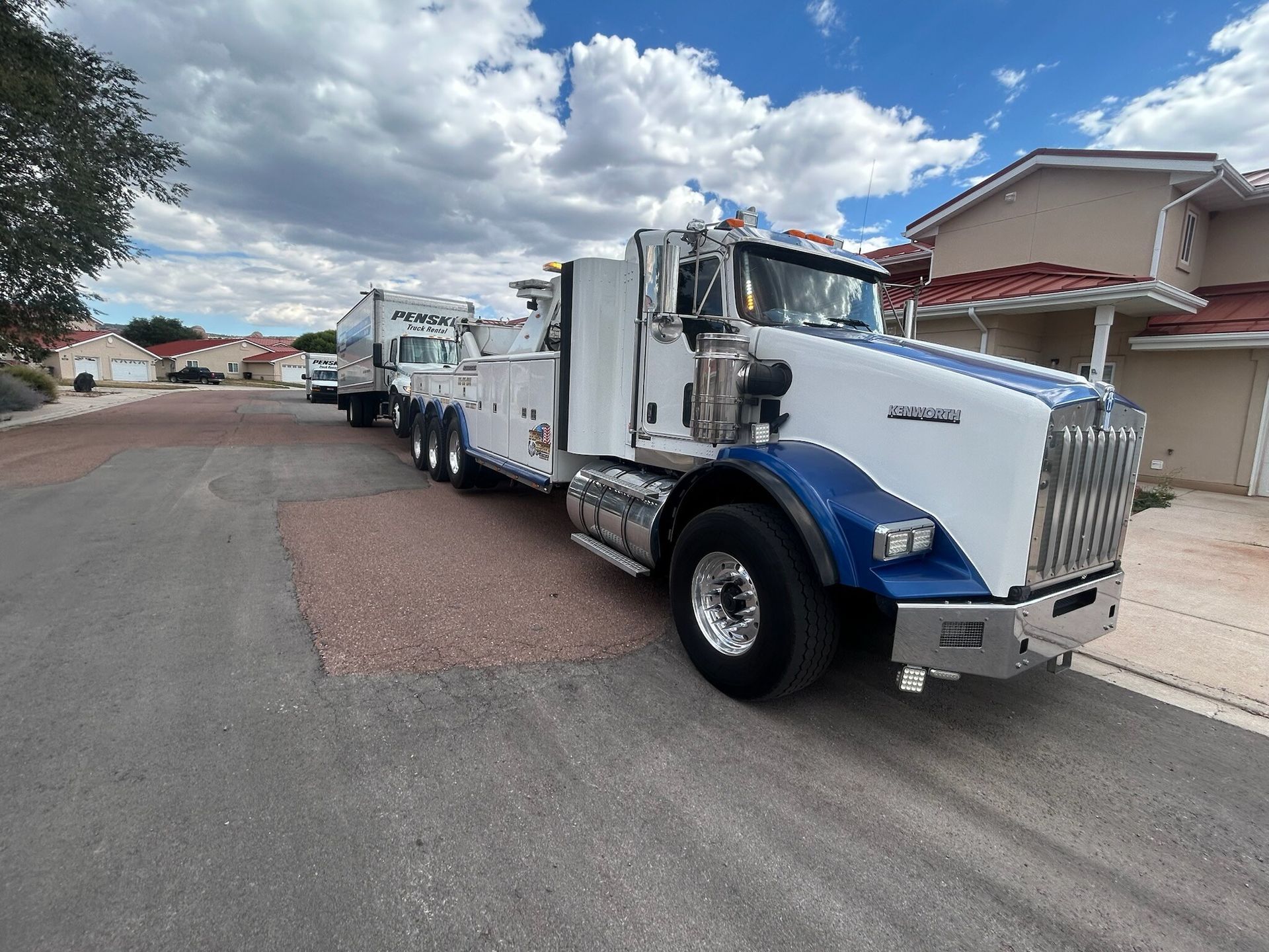 A white and blue tow truck is parked on the side of the road.