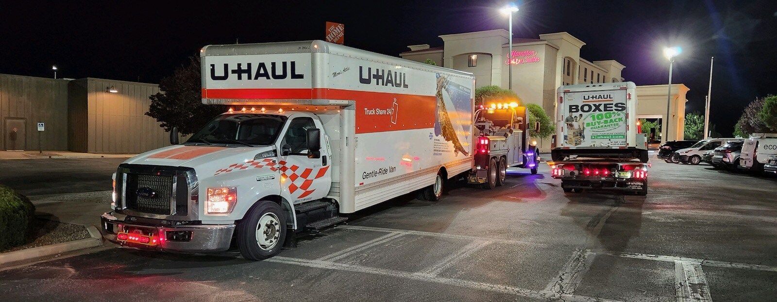 A u-haul truck is parked in a parking lot at night.