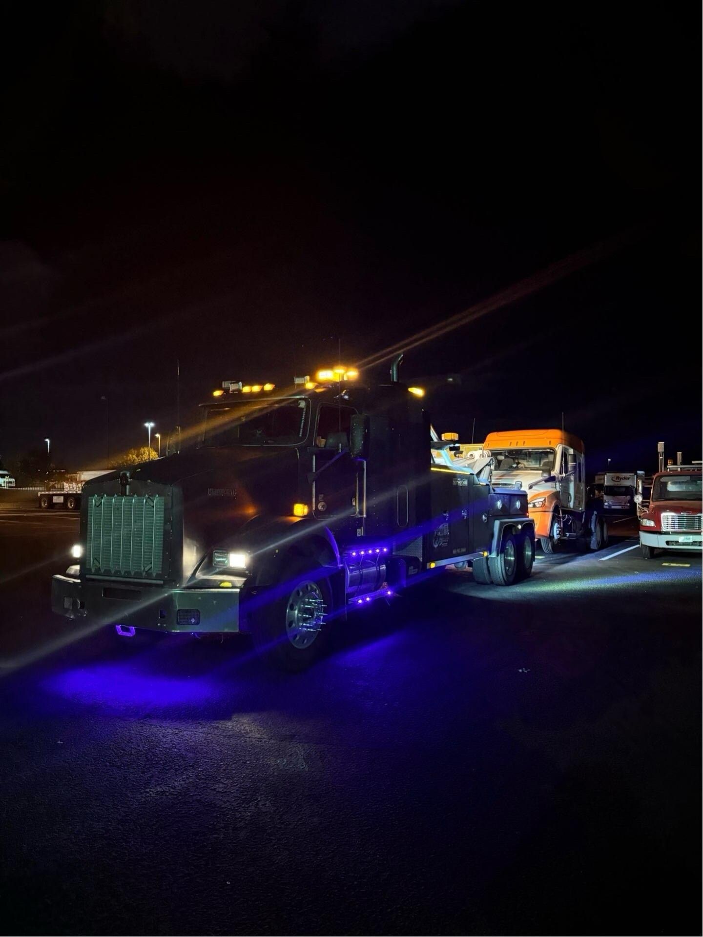 A tow truck is parked in a parking lot at night.
