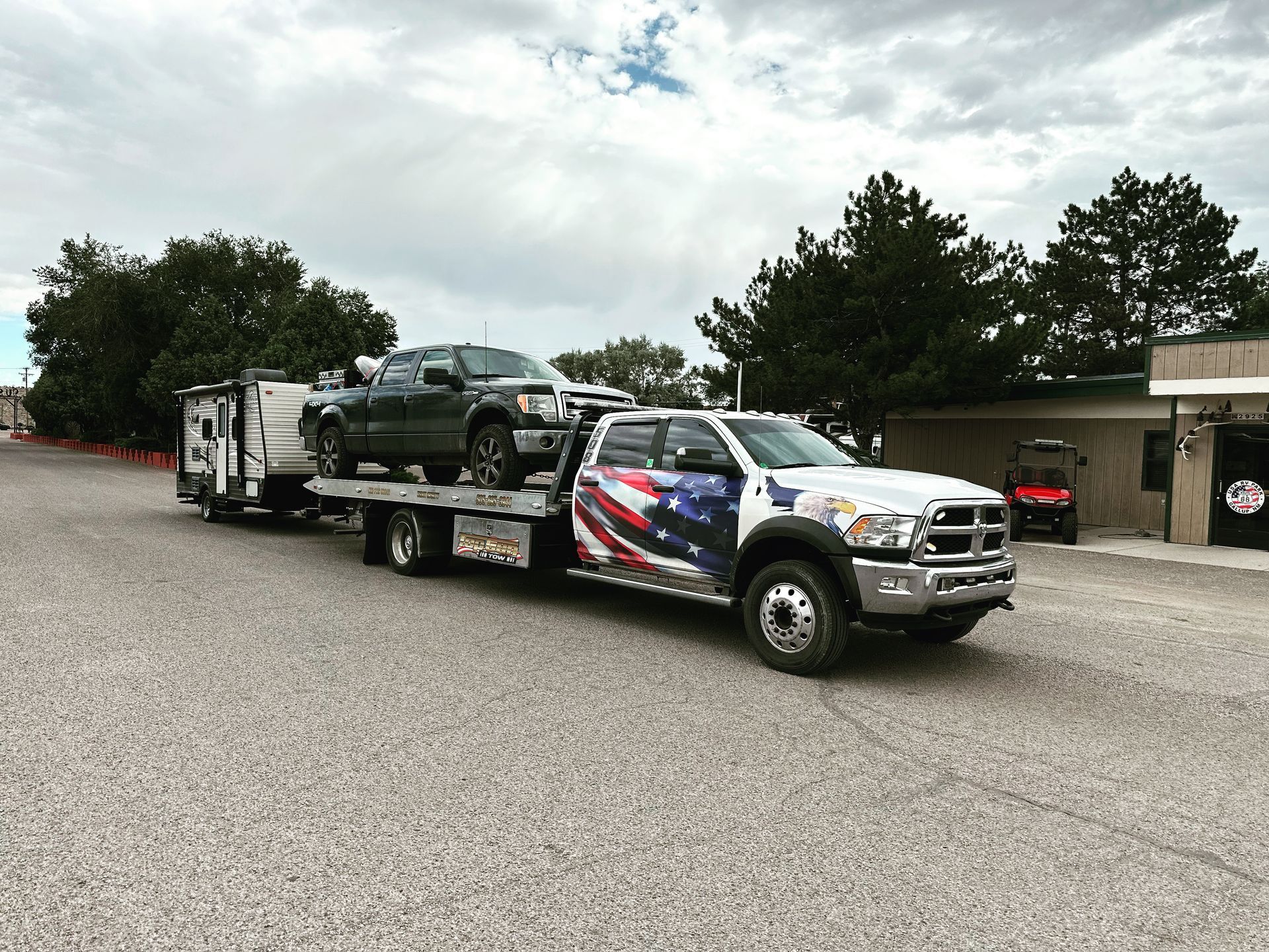 A tow truck is carrying two cars and a trailer.