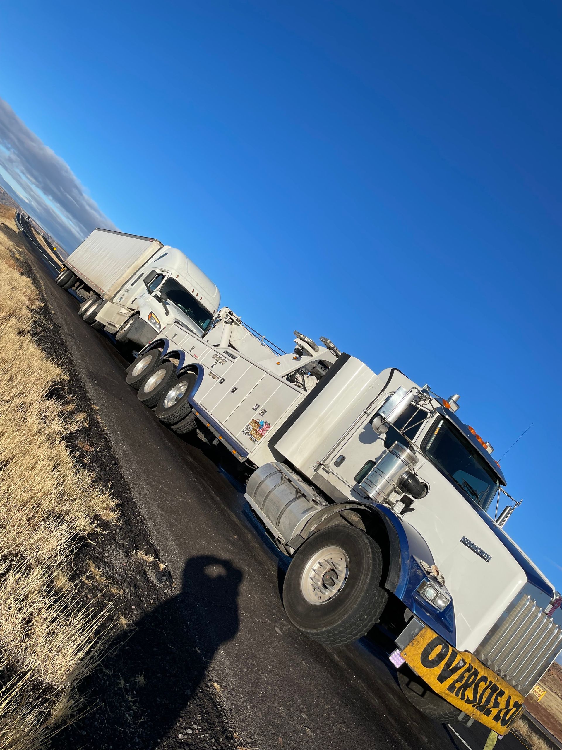 A white semi truck is parked on the side of the road.