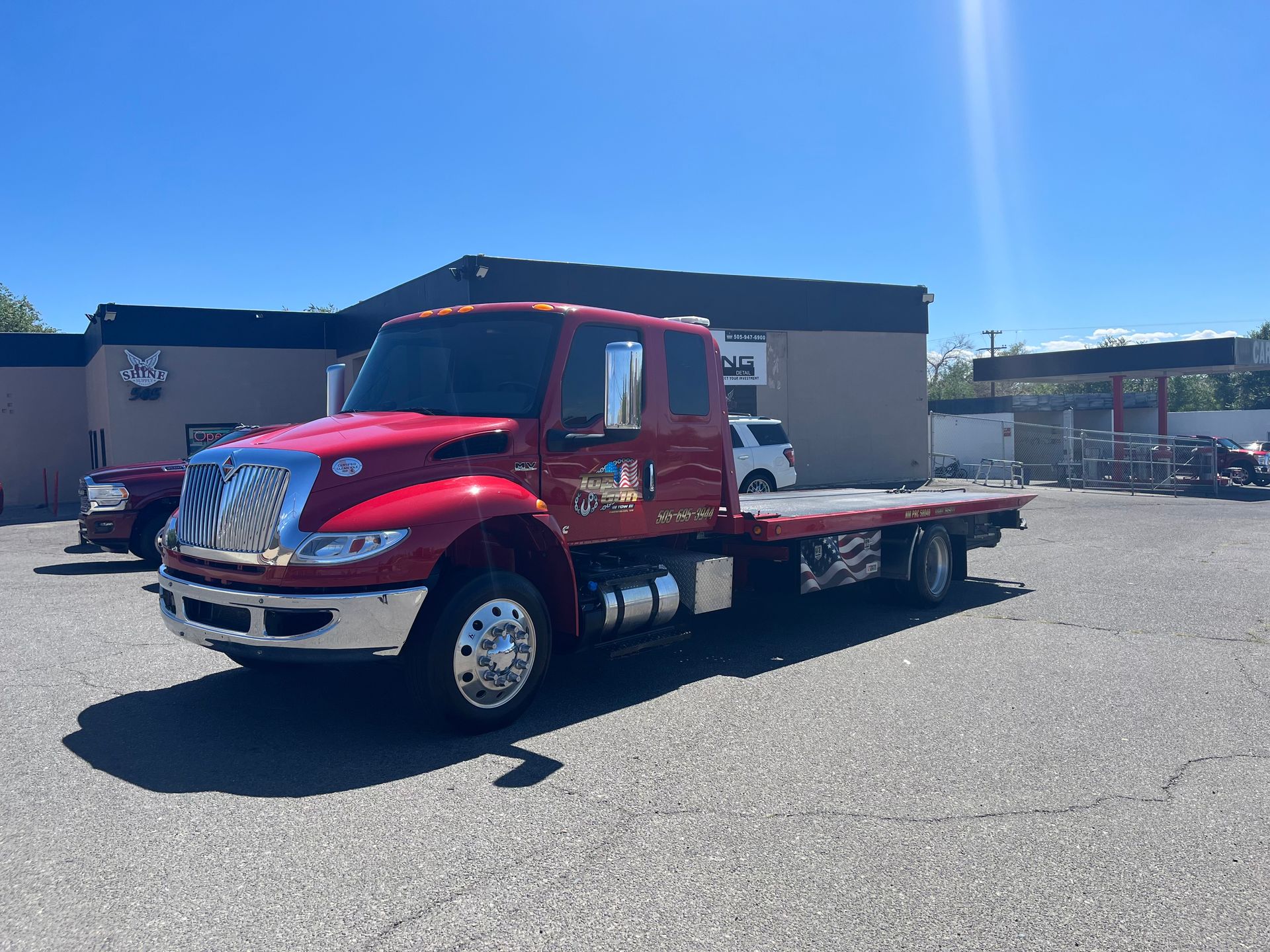 A red tow truck is parked in a parking lot in front of a building.