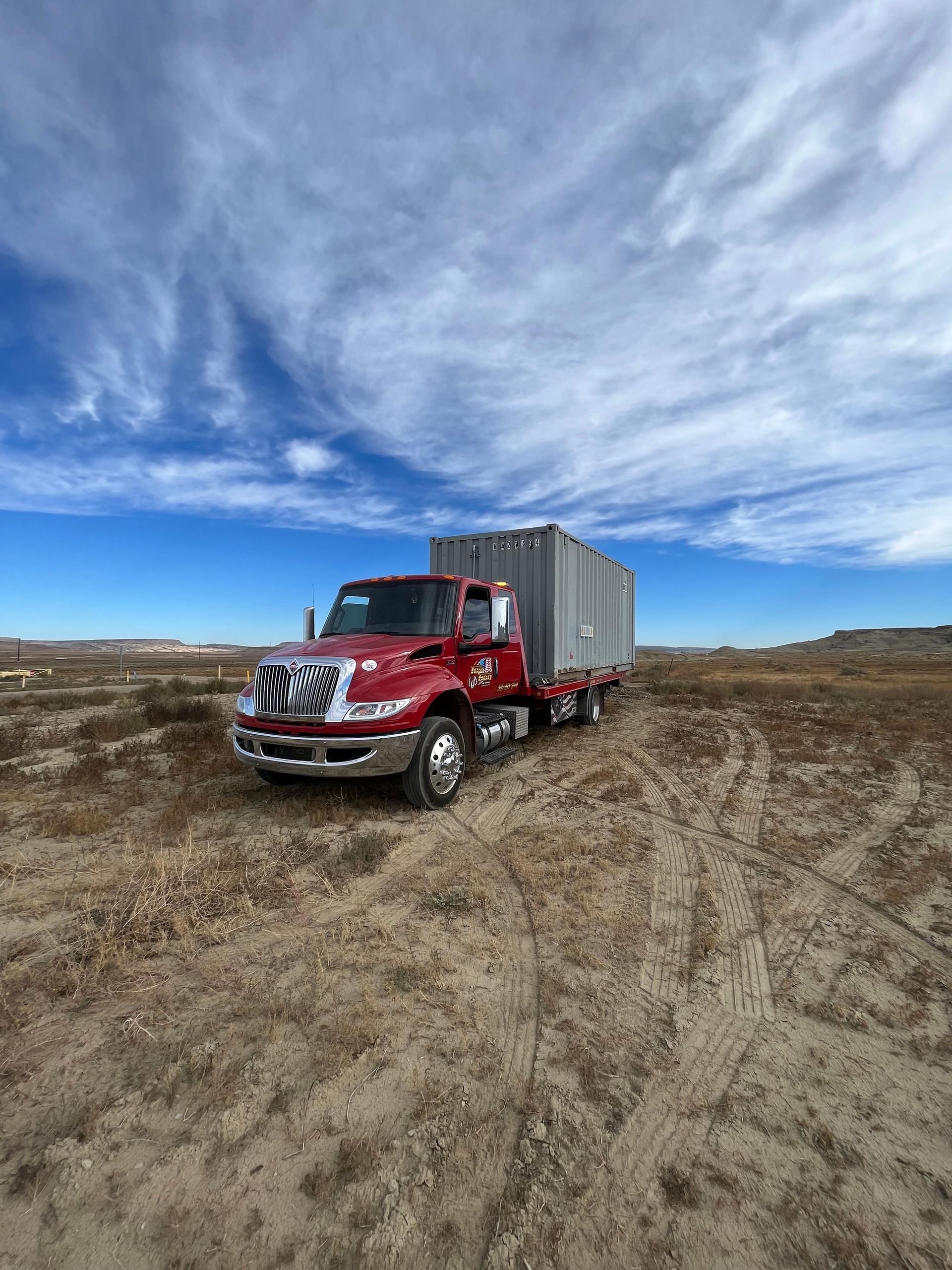 A red truck is parked in the middle of a desert.