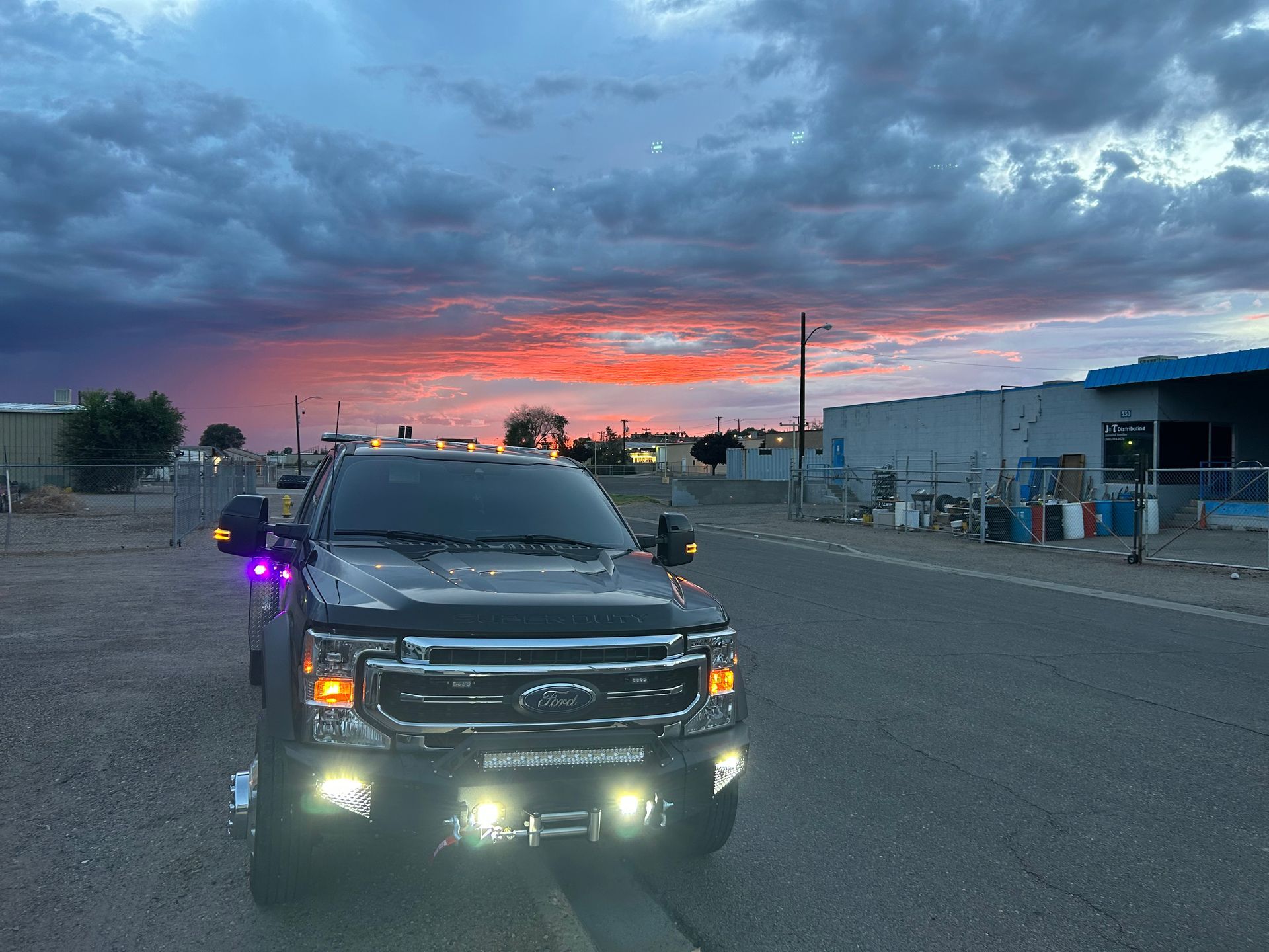 A truck is parked on the side of the road at sunset.