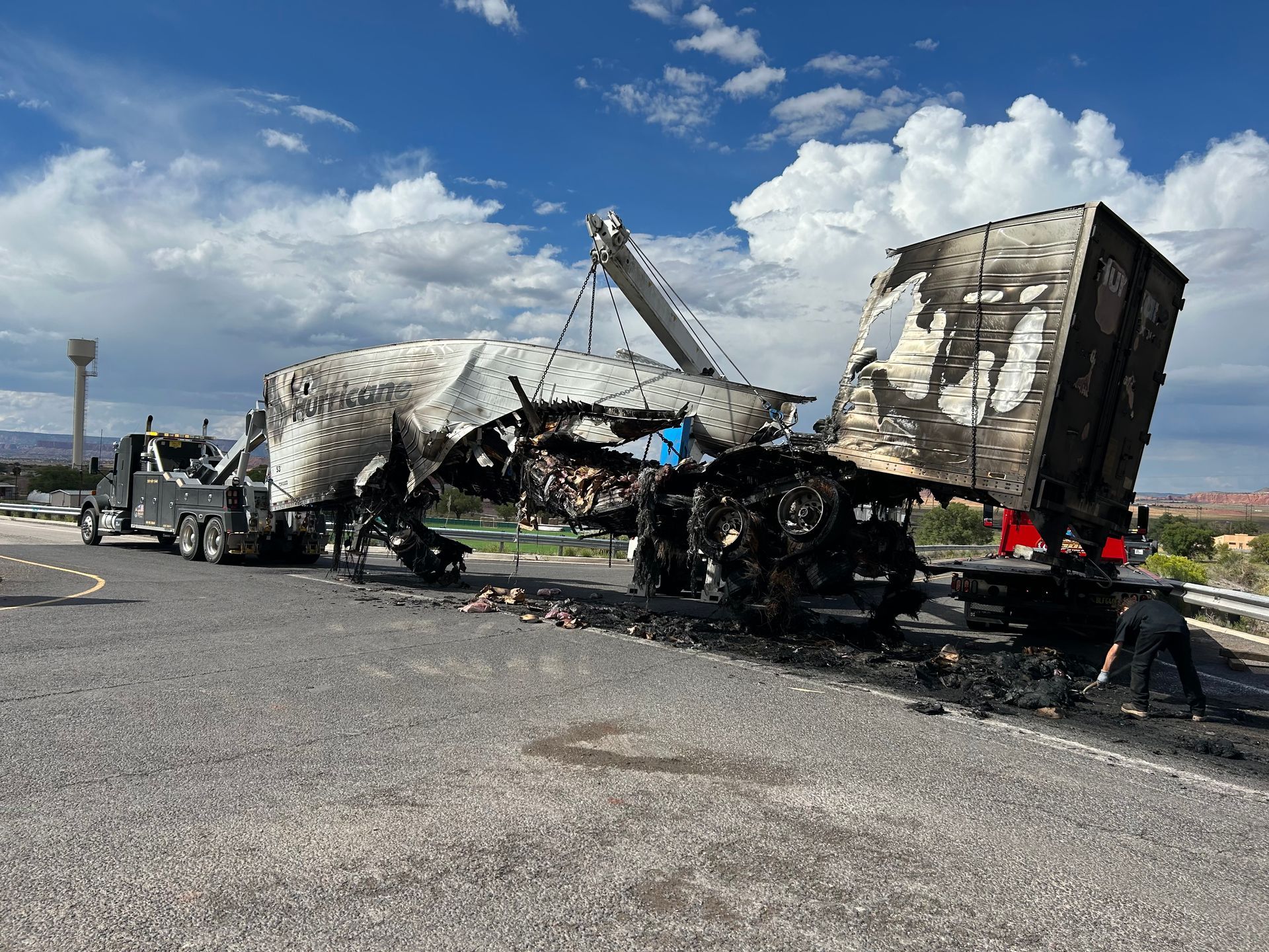 A tow truck is pulling a truck that has been damaged by a fire.