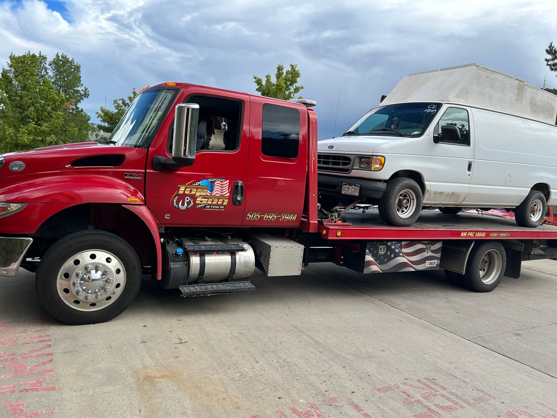 A red tow truck is towing a white van.
