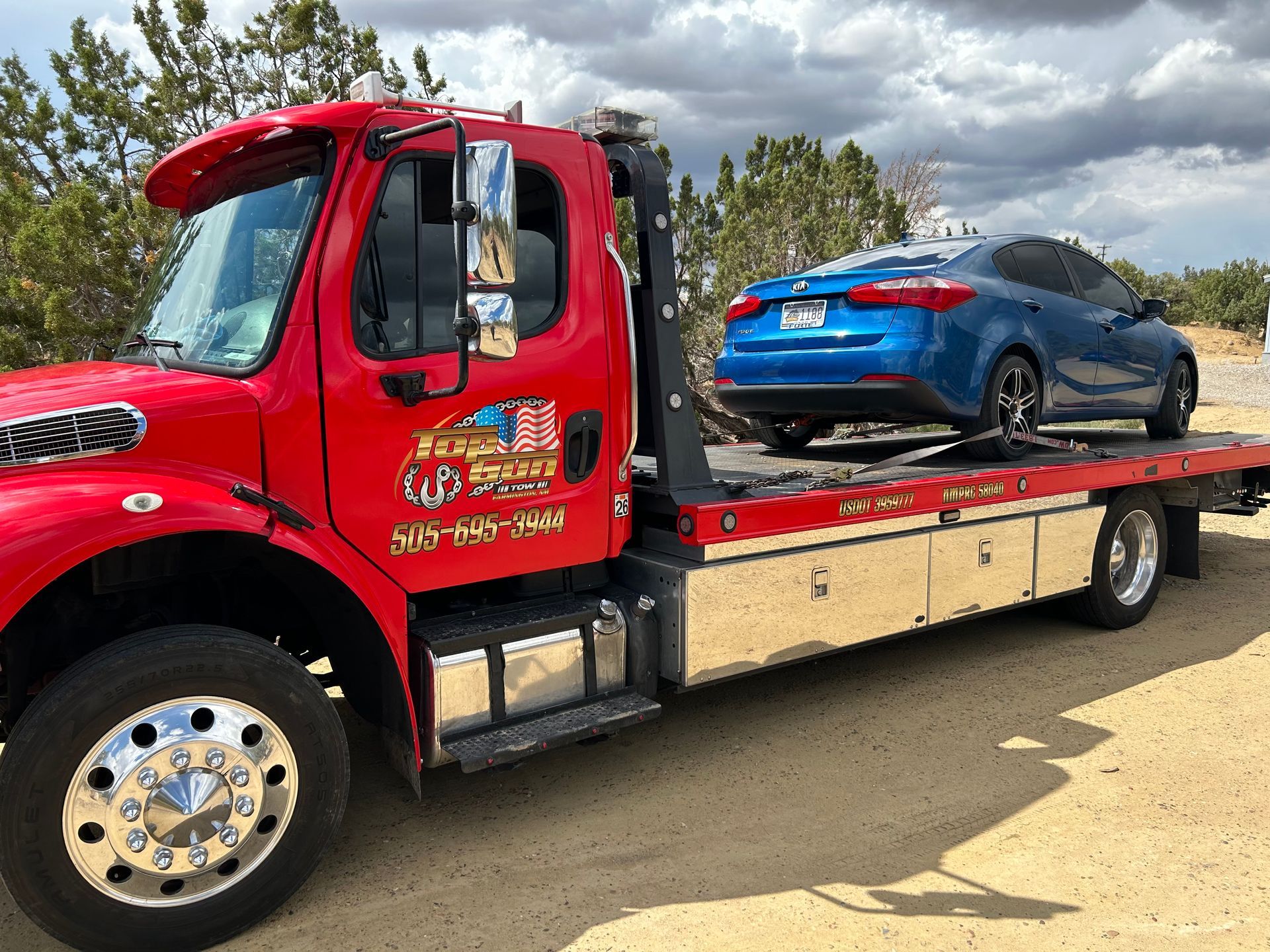A red tow truck is towing a blue car.