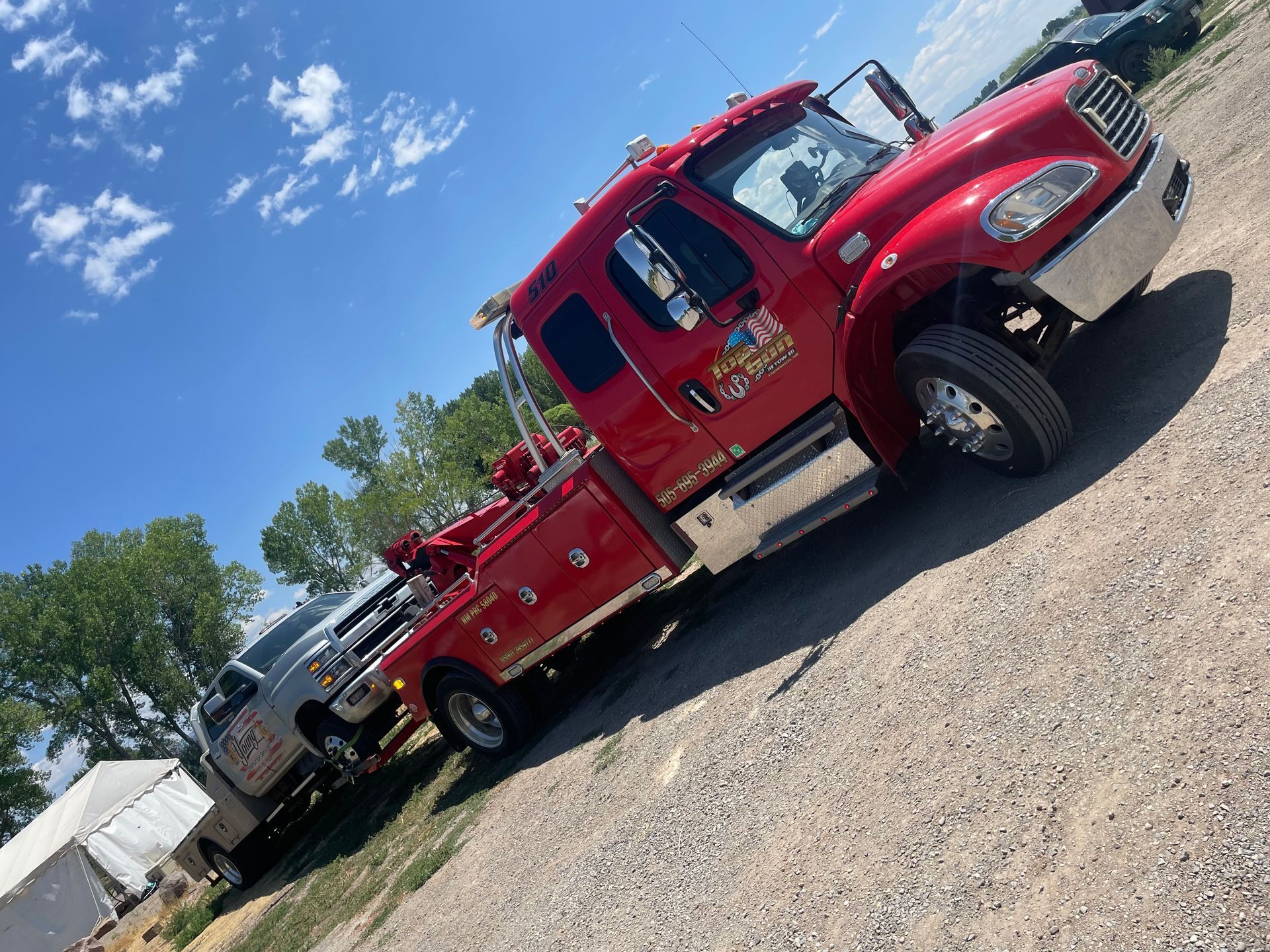 A red tow truck is parked in a gravel lot.