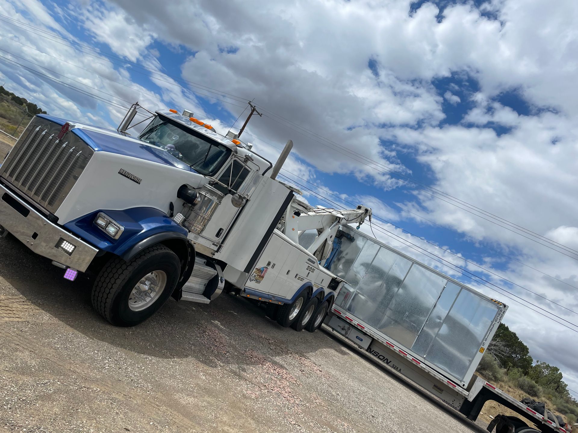 A tow truck is parked on the side of the road next to a trailer.