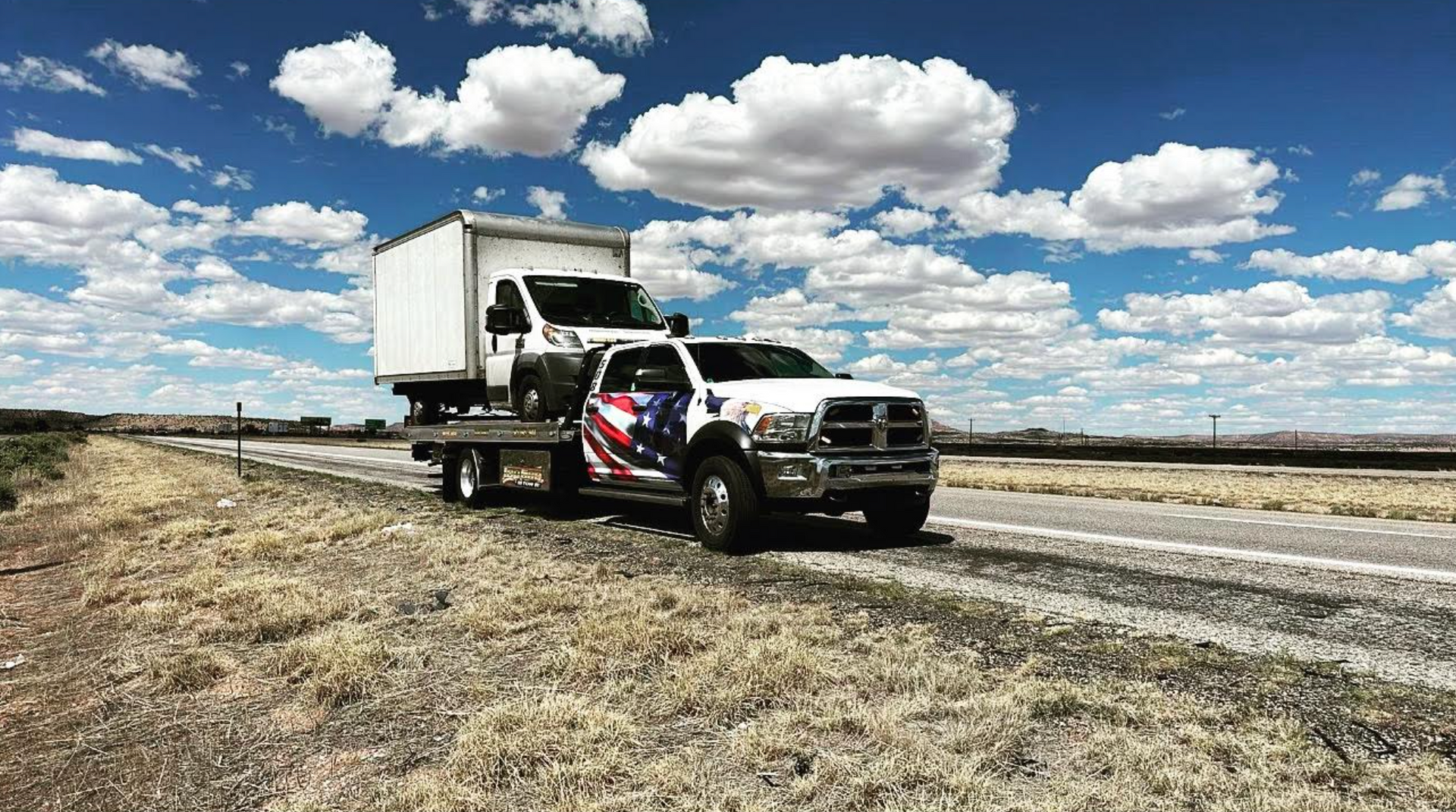 A tow truck is driving down the road with a box on the back of it.