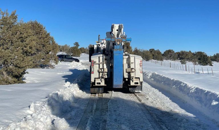 A truck is driving down a snow covered road.