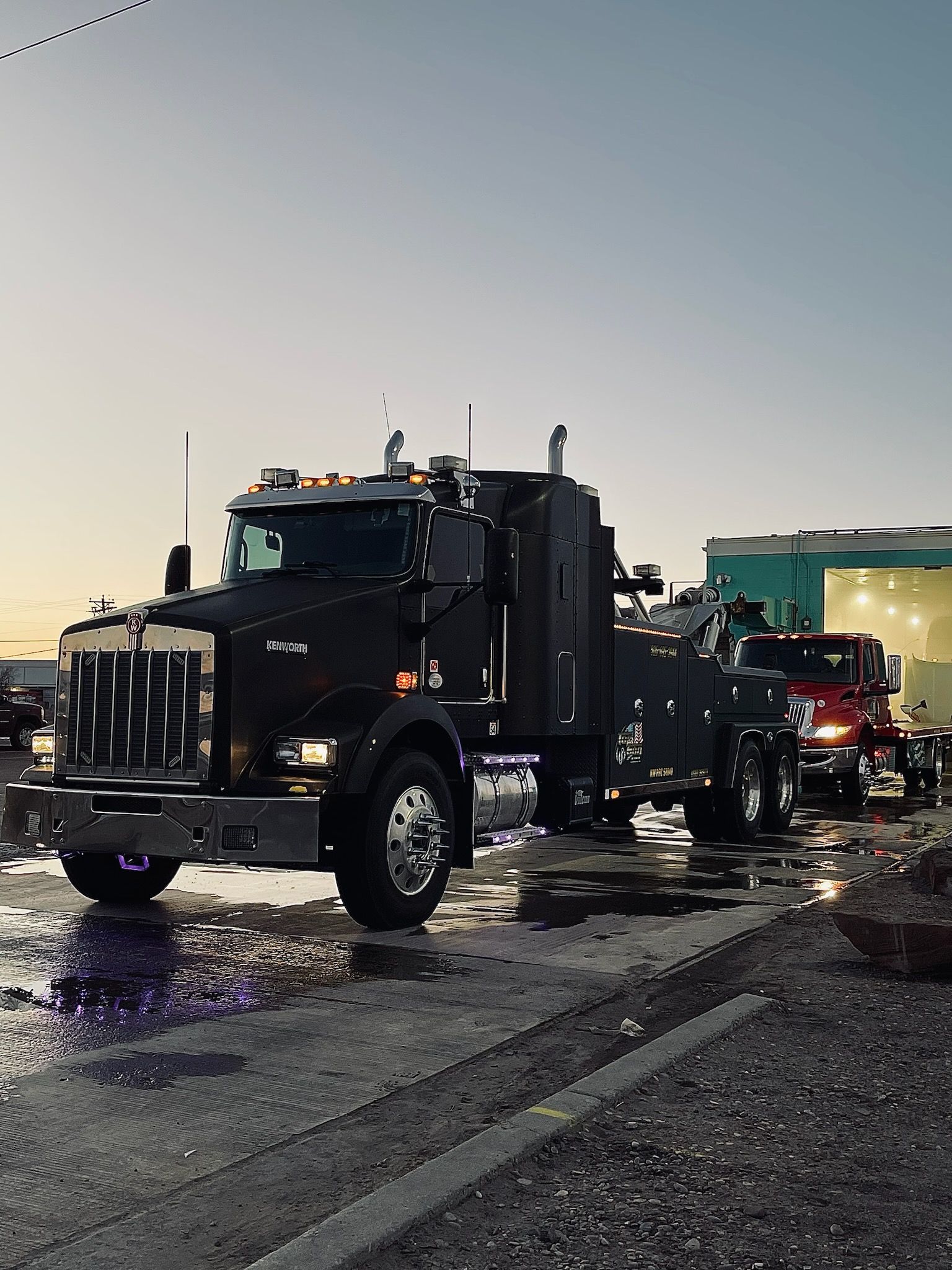 A black tow truck is parked on the side of the road