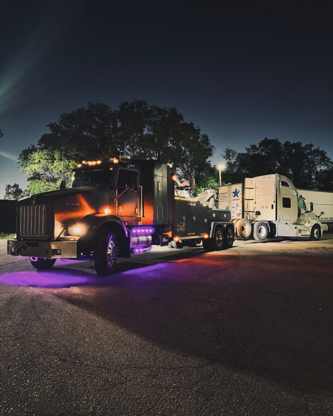 A semi truck is parked in a parking lot at night