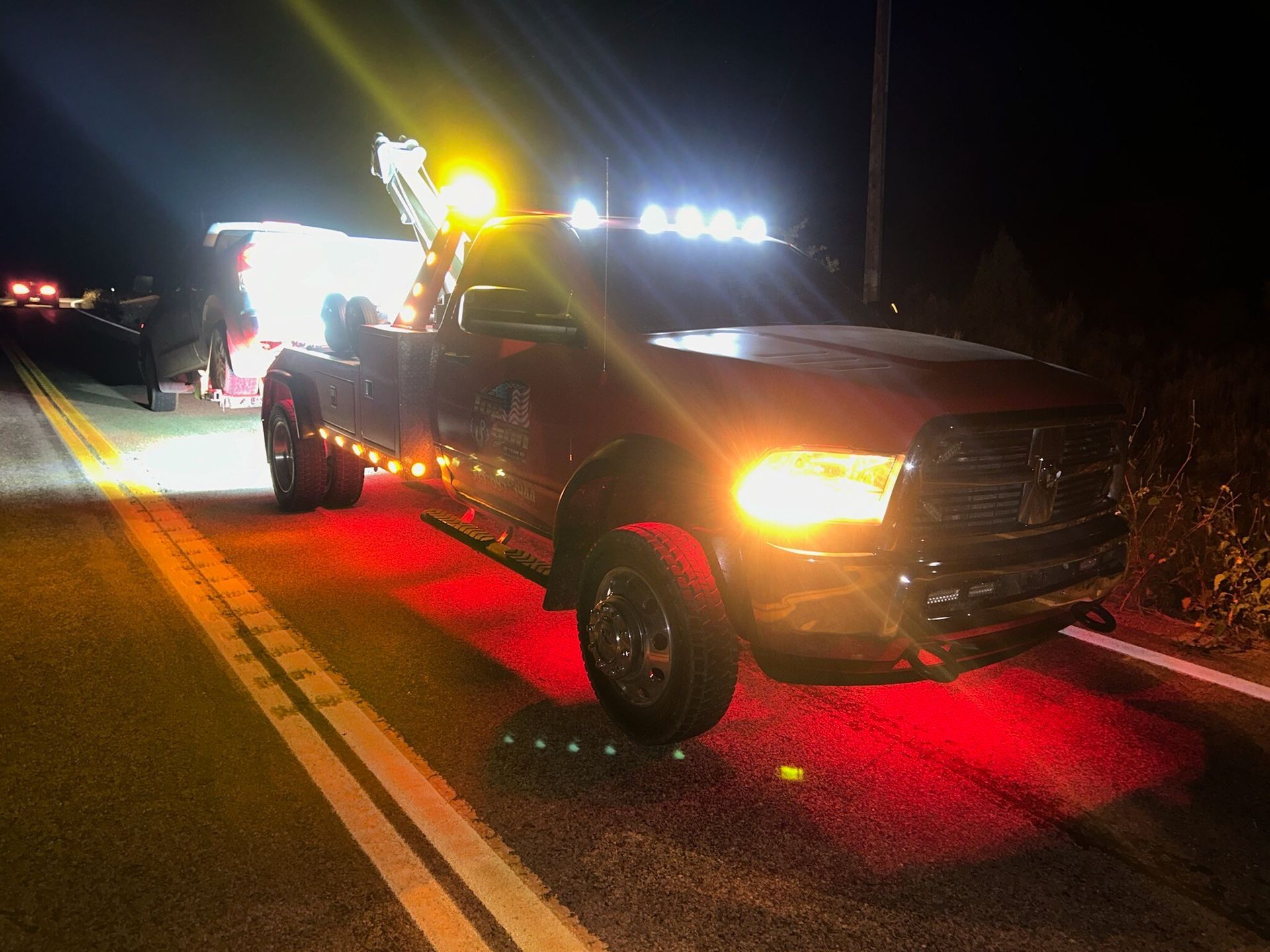 A tow truck is parked on the side of the road at night.