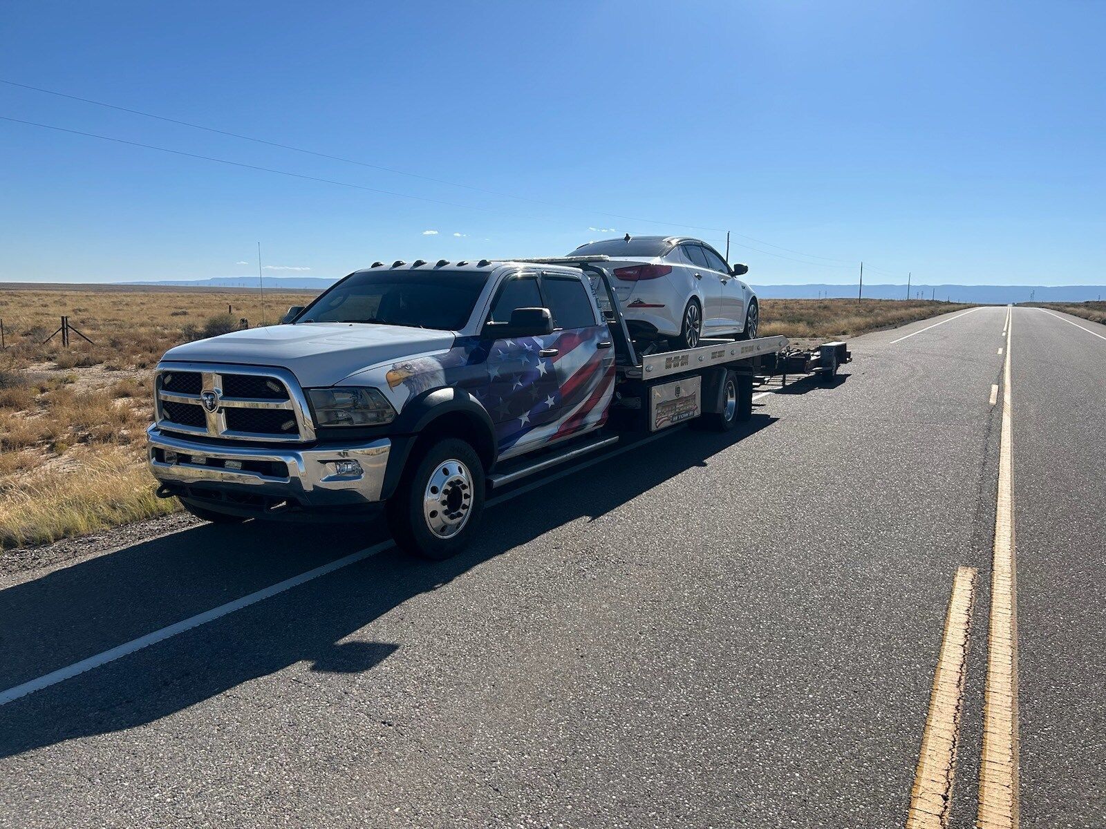 A tow truck is towing a car down a road.