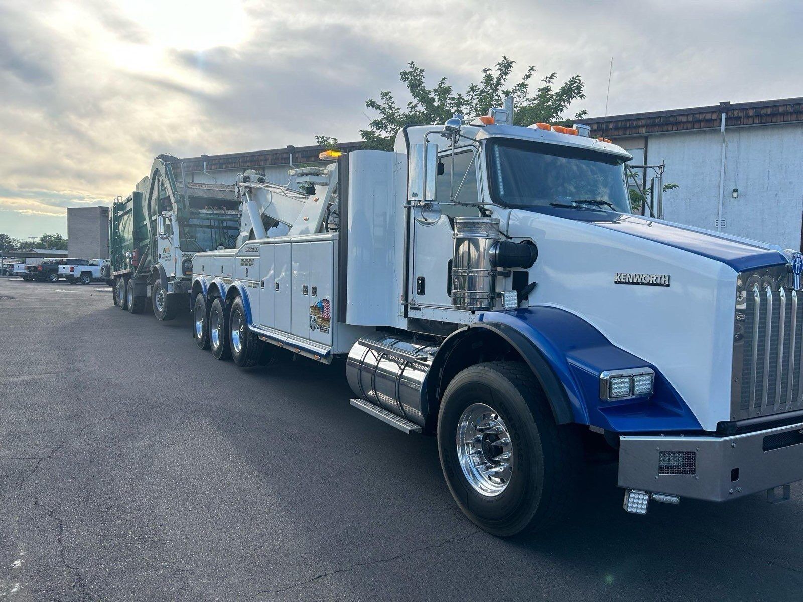 A white and blue tow truck is parked on the side of the road.