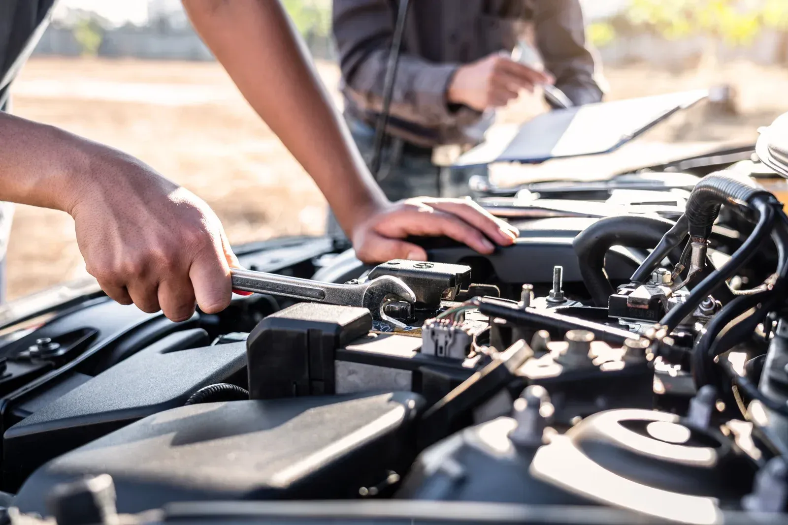Two men are working on the engine of a car.