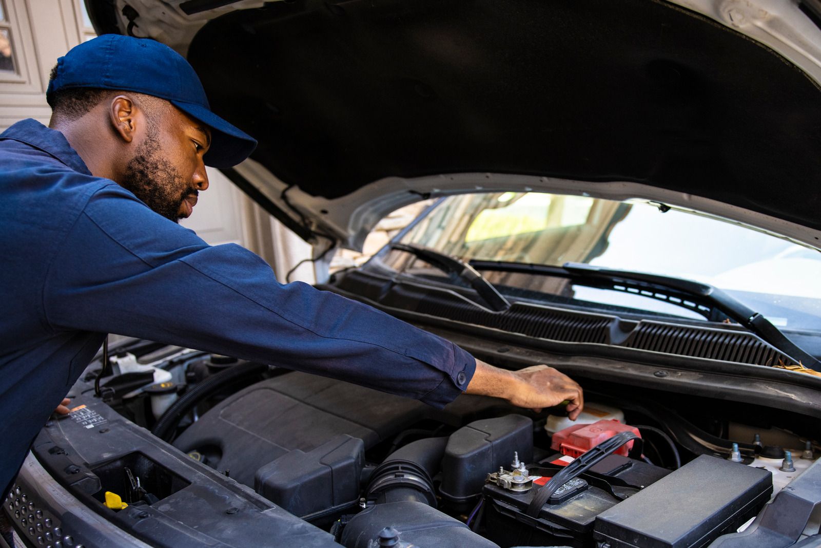 A man is working on the engine of a car with the hood open.