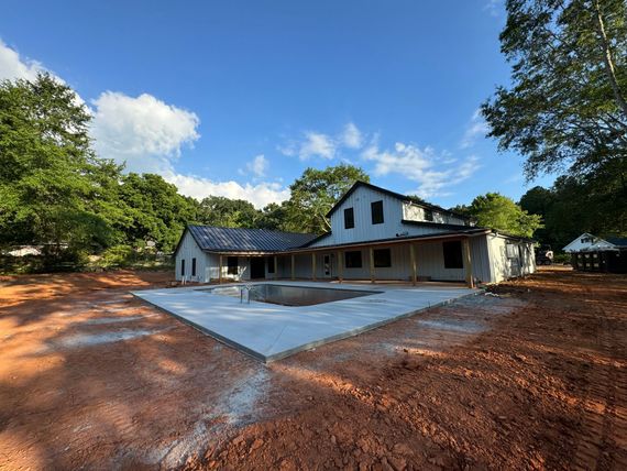 A house under construction is surrounded by dirt and trees