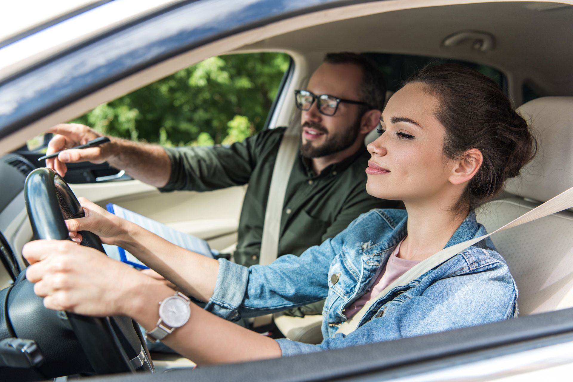 A cheerful student and a teacher in a car, performing on-road driving lessons.