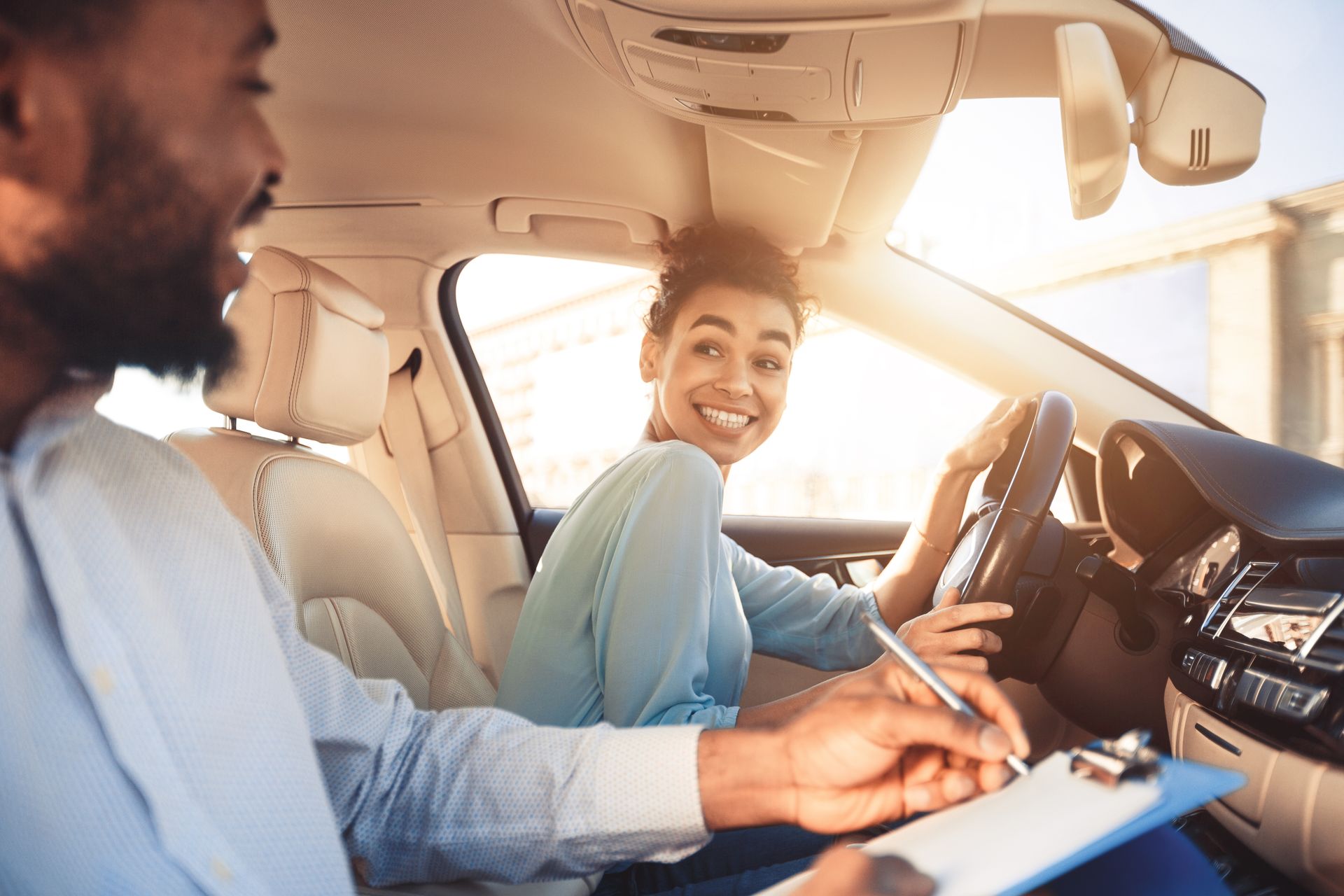 Happy woman in examination car, smiling at a male instructor.