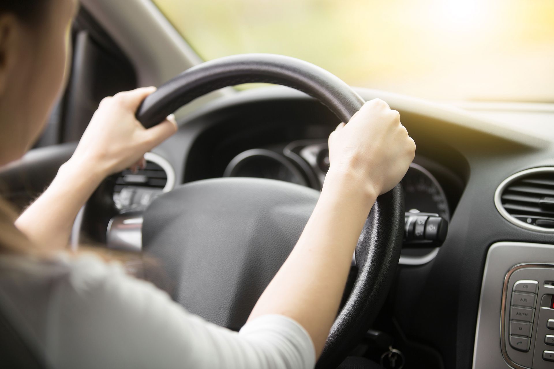 Close-up of female hands on a steering wheel. 