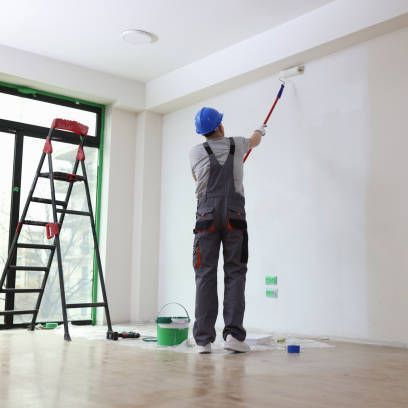Professional painter paints office wall with roller brush.