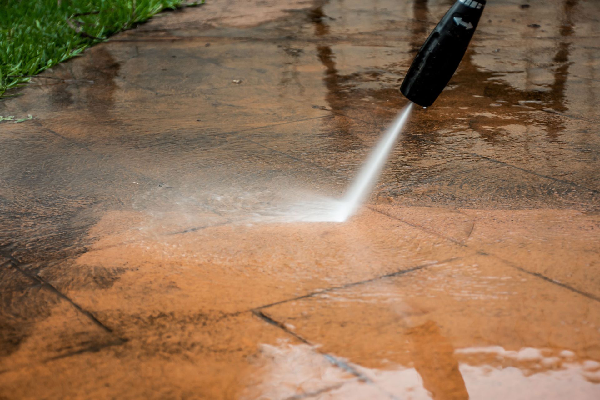 A person is using a high pressure washer to clean a patio.