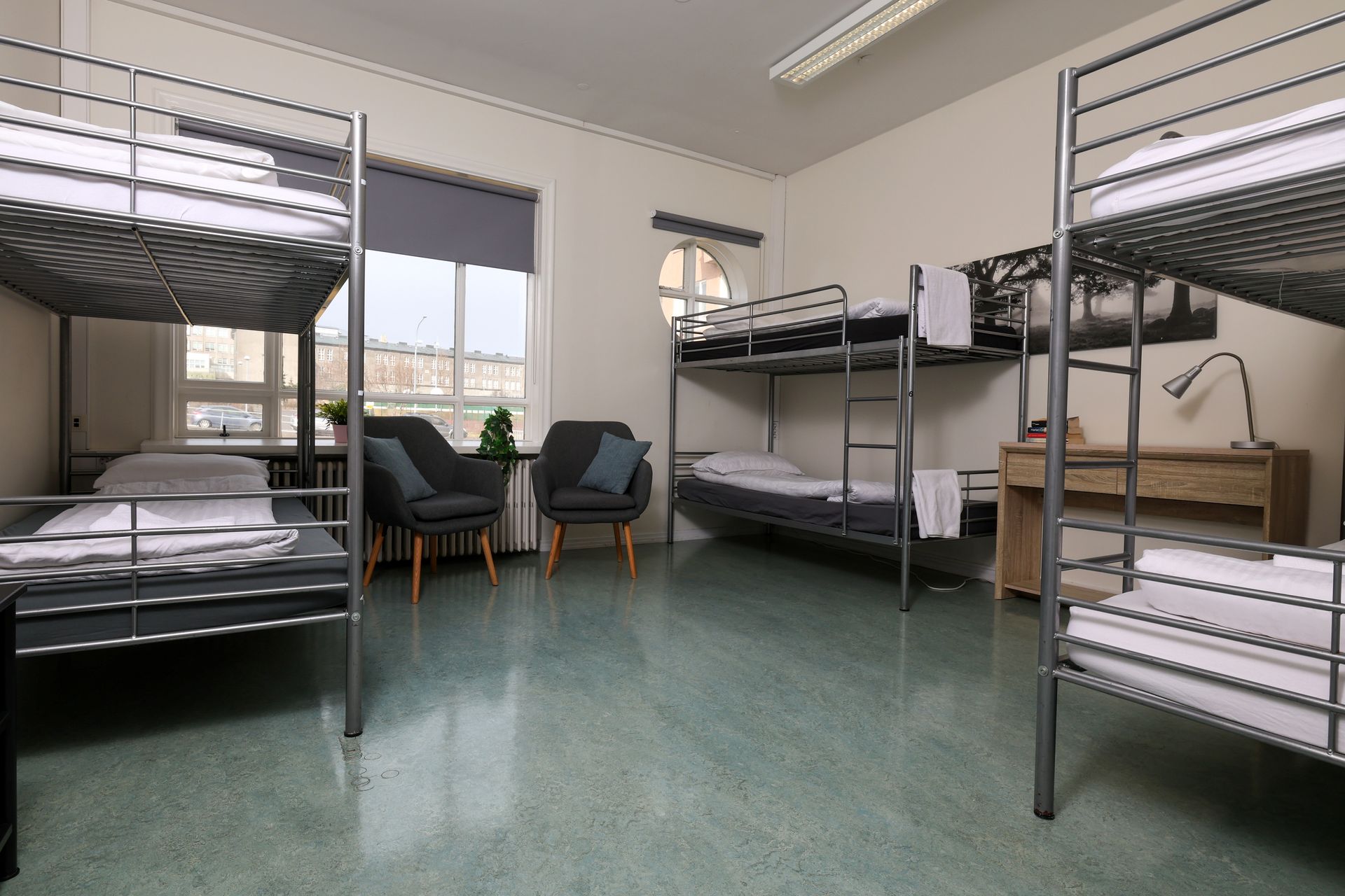 A dorm room with bunk beds , chairs and a desk.