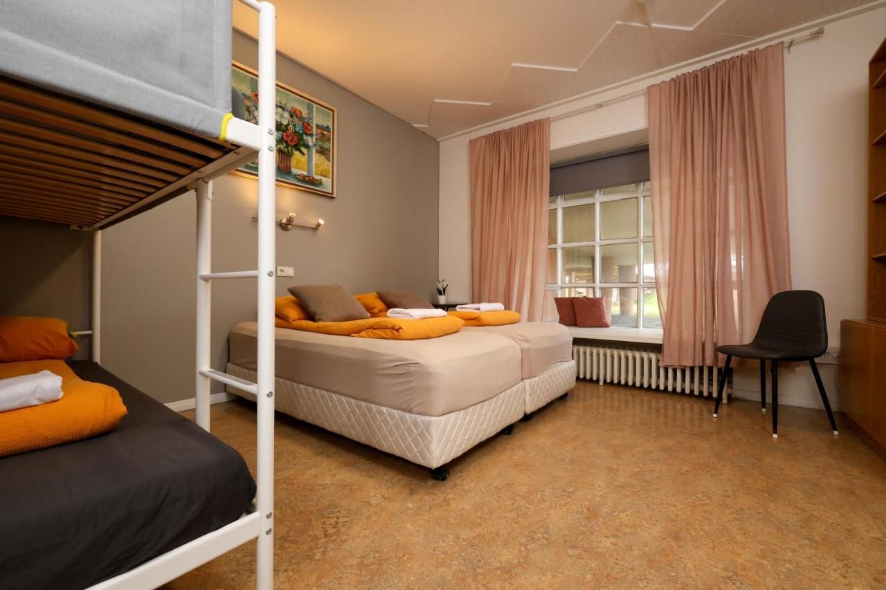 A bedroom with bunk beds , a chair and a window.