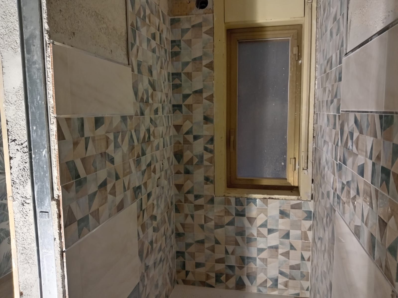 un bagno con piastrelle geometriche e una finestra .