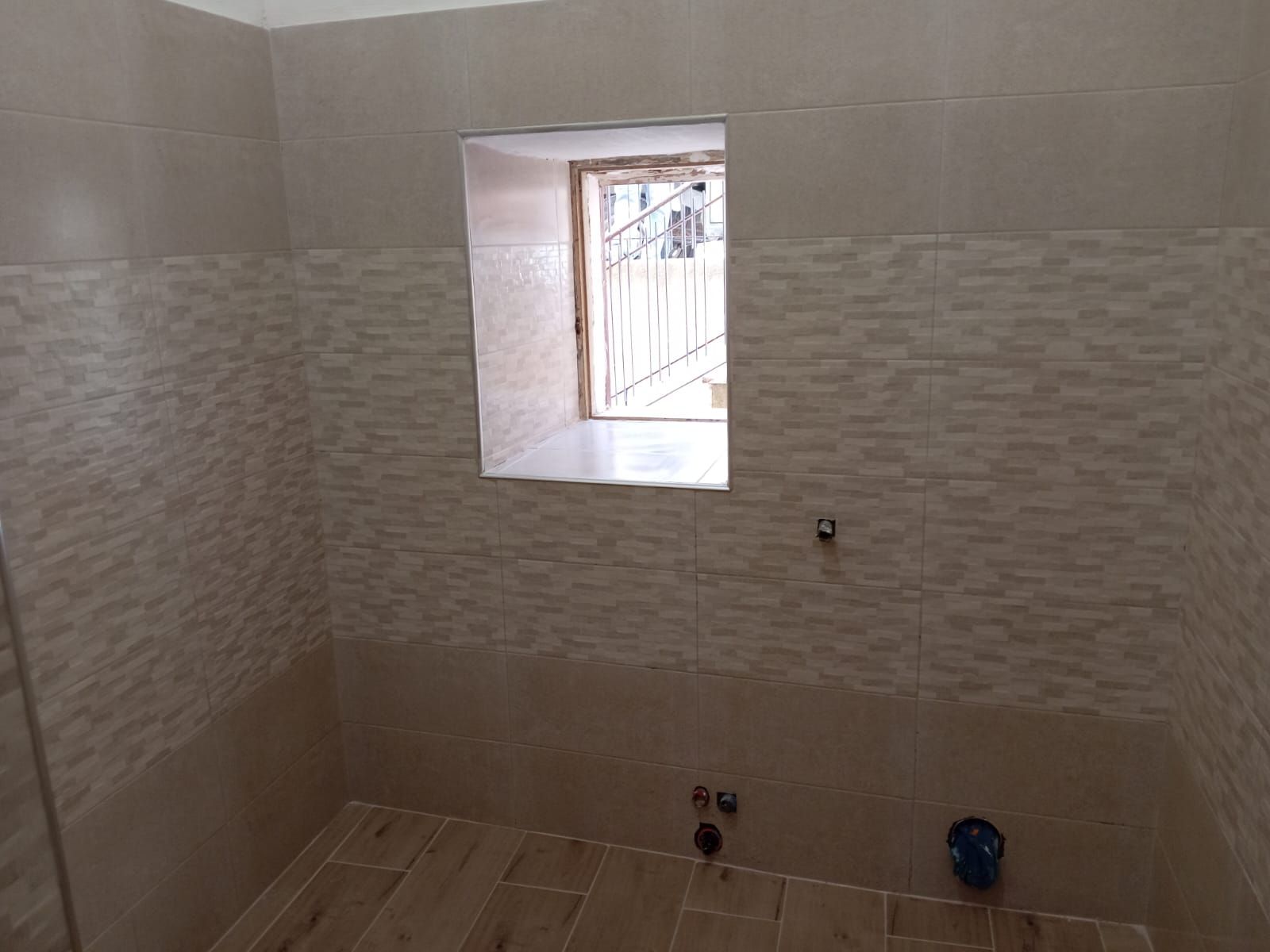un bagno con piastrelle beige e una finestra .