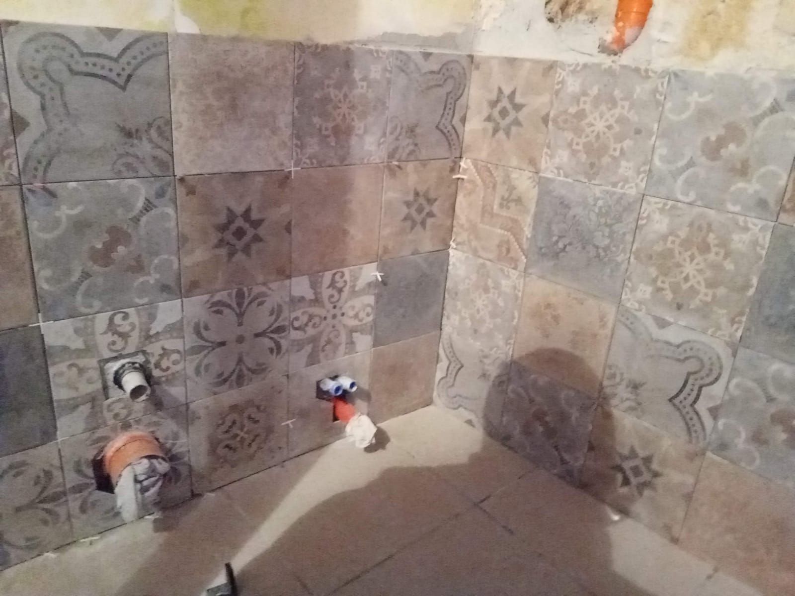 un angolo di una stanza con piastrelle e un tubo .