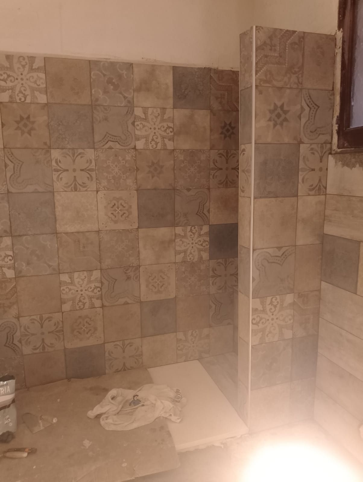 un bagno con piastrelle marroni e bianche e una finestra .