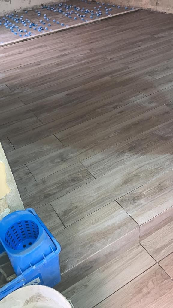 un primo piano di un pavimento in legno con piastrelle e un mop blu .