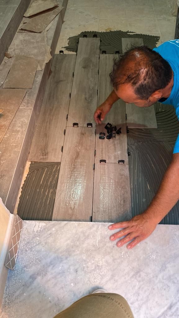 un uomo sta mettendo piastrelle su un pavimento di legno .