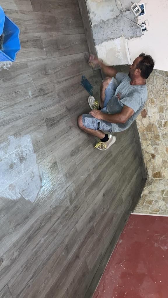 un uomo è seduto su un pavimento di legno con una spatola .