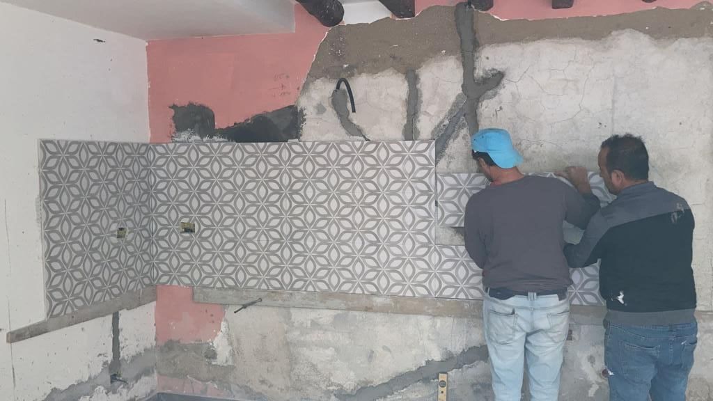 un gruppo di uomini sta lavorando su un pavimento di piastrelle .