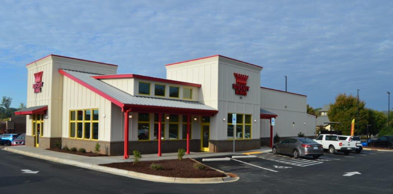 A restaurant with a red roof and trim, and a drive-thru, with cars parked out front.
