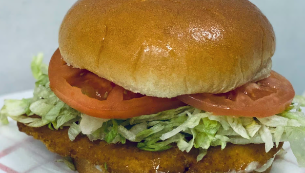 Chicken sandwich on a bun with lettuce and tomato.